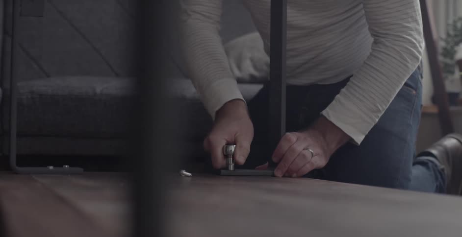 A man assembles a table on a living room floor