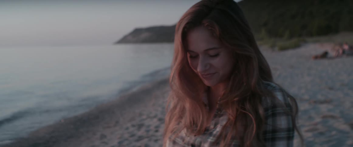 A woman stands on a beach at sunset
