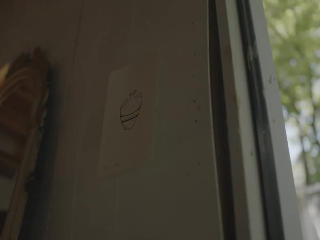 A white door frame has a simple drawing of a jar or vase taped to it with tape