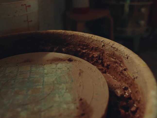 Wet clay fills the outside bowl of a pottery wheel in a workshop