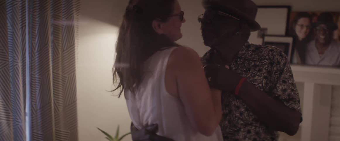 A man and woman dance at home