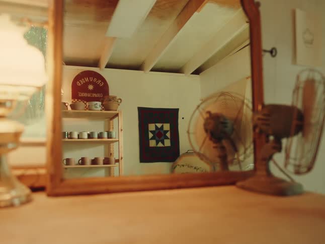 Reflection of a woman near ceramic shelves seen through the mirror