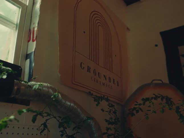 Metallic duct with climbing plants runs along a wall decorated with a poster