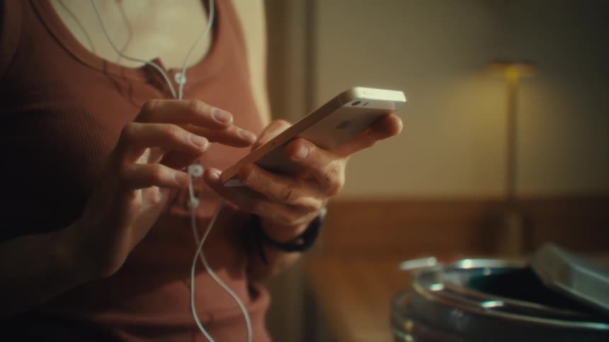 Close up of a young woman using a mobile phone while standing indoors in a kitchen during daytime