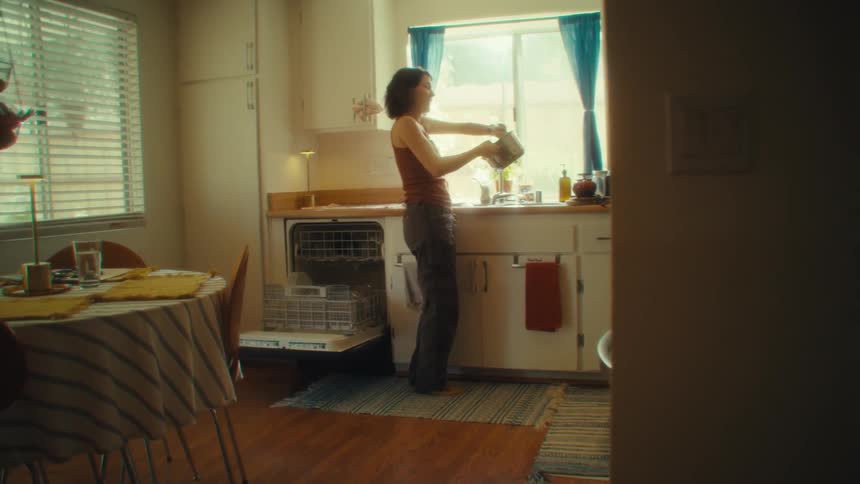 The woman is dancing and having fun while doing dishes