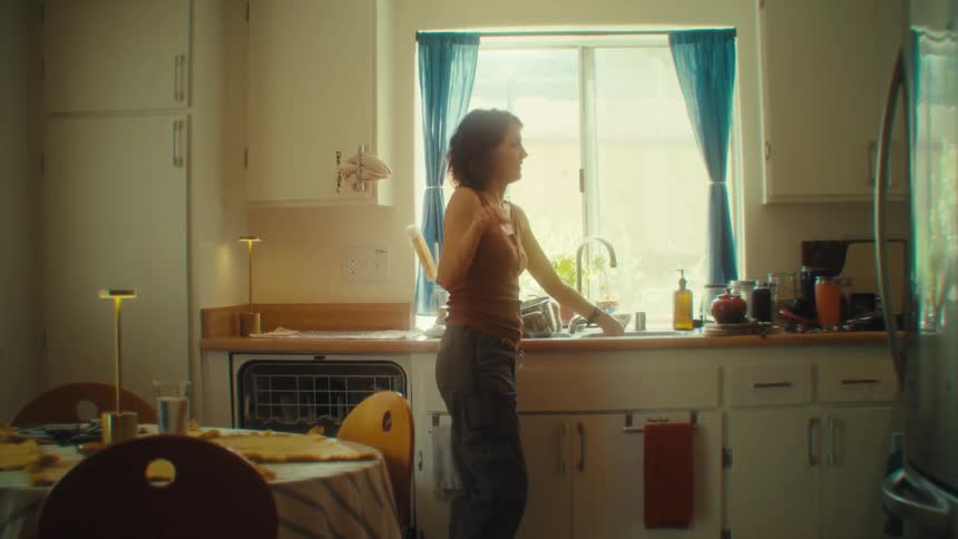 The woman is dancing as she does dishes
