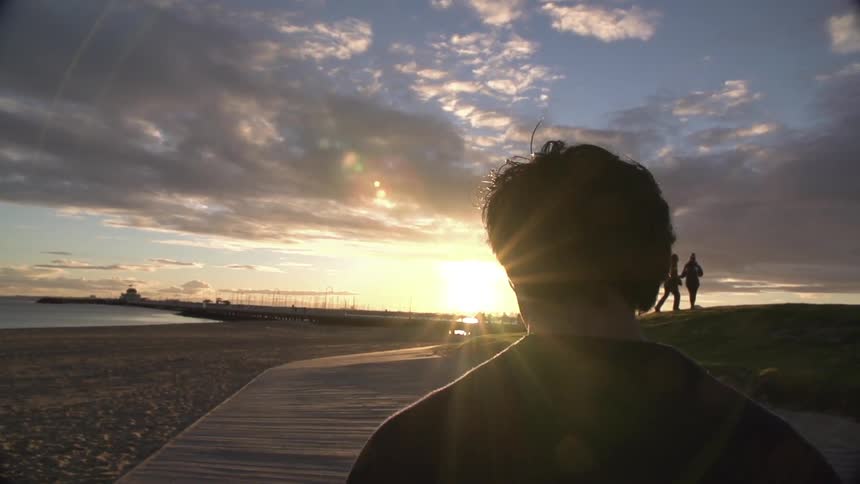 Man walks down a path by the beach