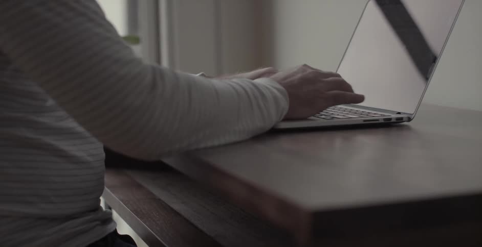 A person types on a laptop at desk