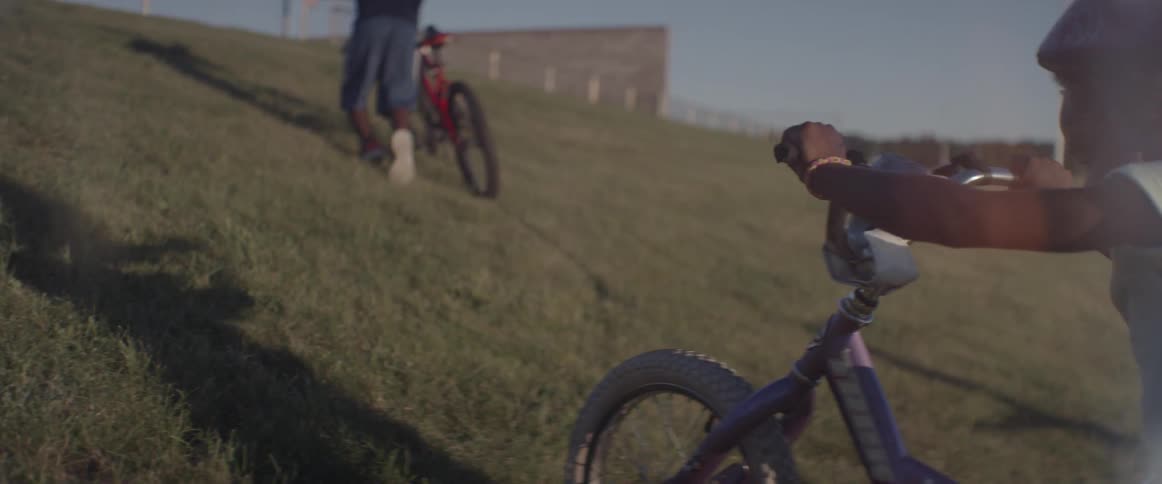 Two children push bicycles up a hill