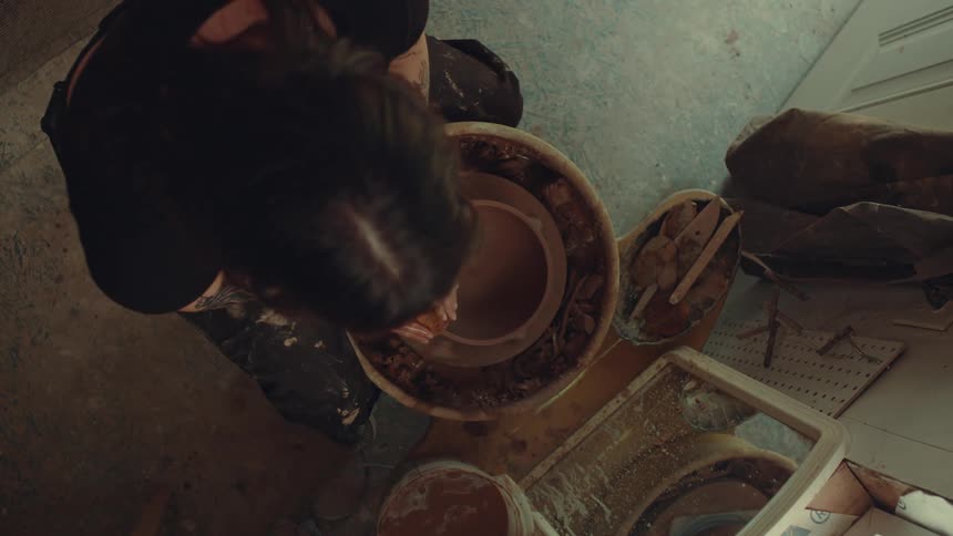 Person shapes clay on a pottery wheel viewed from above