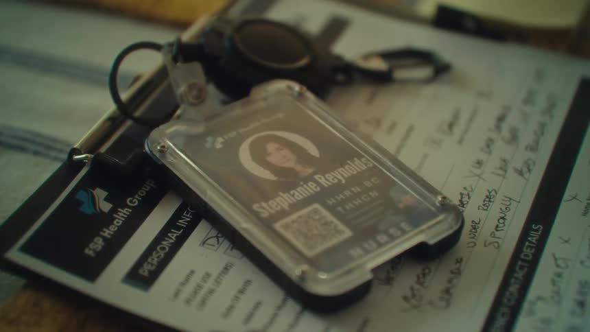 Nurse badge with keychain rests on a clipboard with filled forms