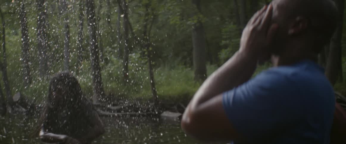 Men splash in a lake surrounded by trees