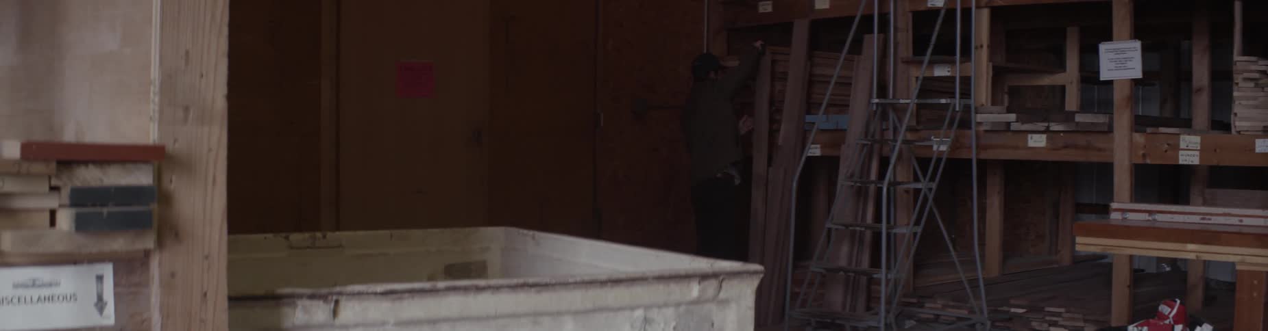 A man descends a ladder with a piece of lumber