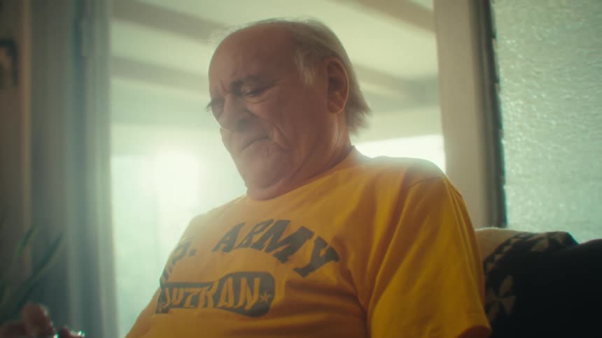 Elderly man sits smiling while holding a tablet