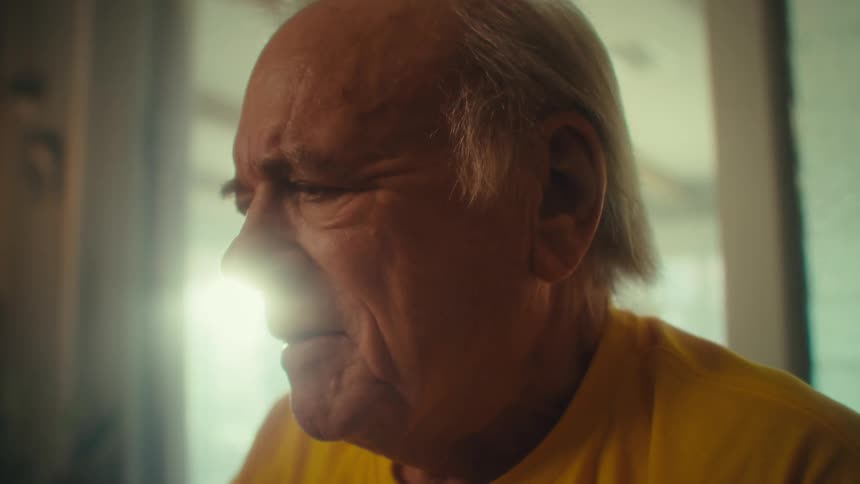 Elderly man with an emotional expression inside an interior space