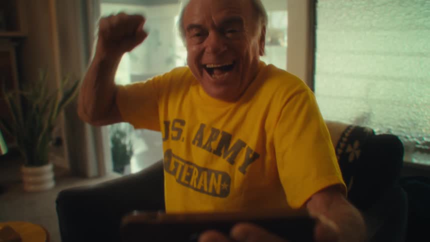 Elderly man laughs joyfully while looking at the tablet