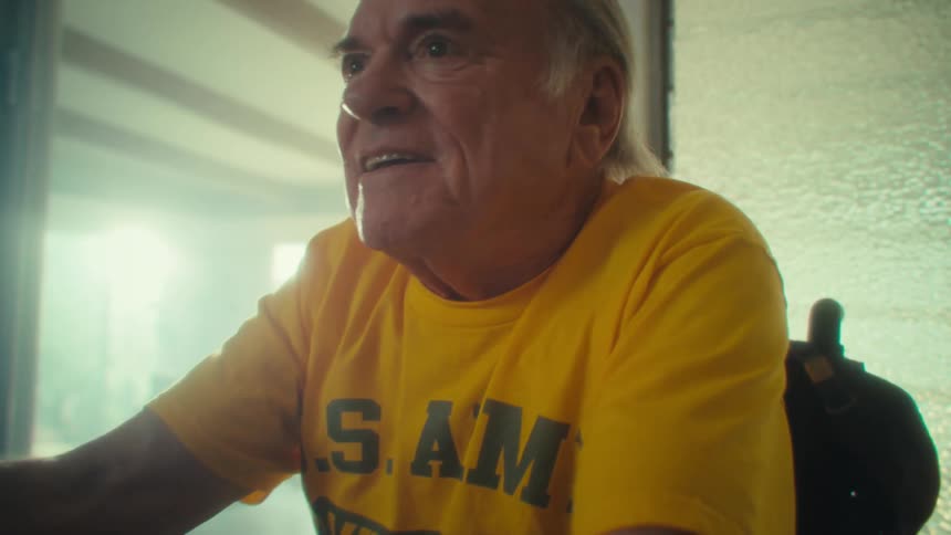 Close up of an elderly man playing video games with a controller while sitting on a wheelchair in a living room during daytime