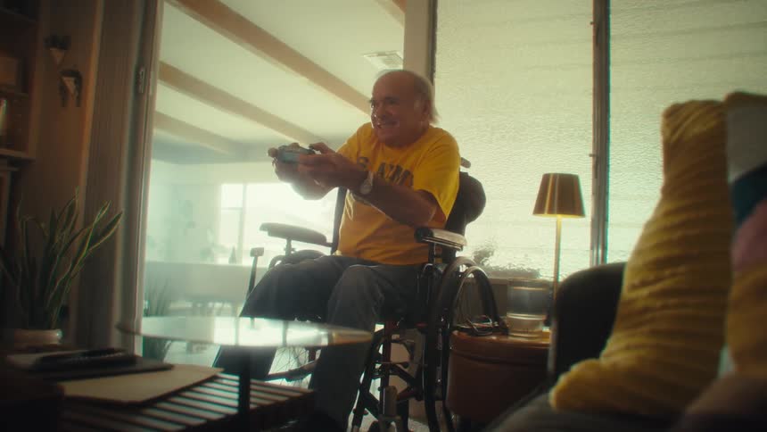 Man in a wheelchair smiles while playing video games with a controller