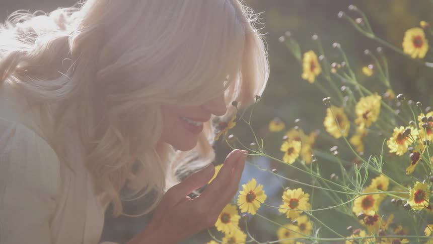 A woman leans down to smell the flowers