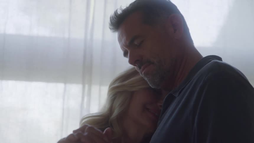 A couple dances closely smiling in soft natural light