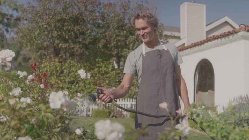 The man is watering the flowers in his garden