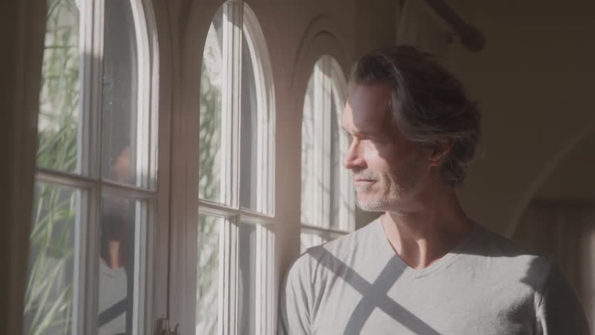 The man leans against the window smiling