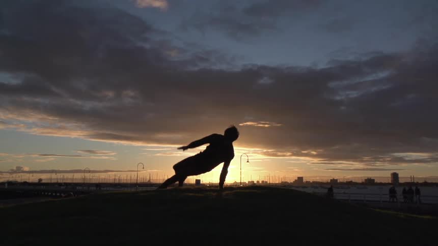 A person break dancing at sunset