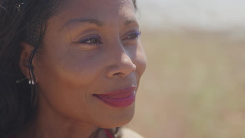 Woman smiles softly while looking at the horizon on a sunny day