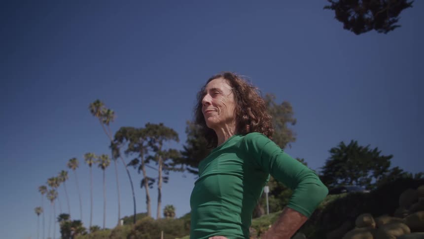 The woman is standing outside on a sunny day