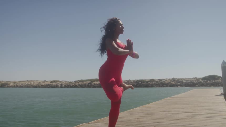 The woman is doing yoga on the pier