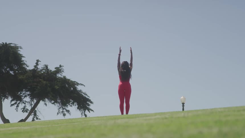 The woman in red is doing yoga on the grass