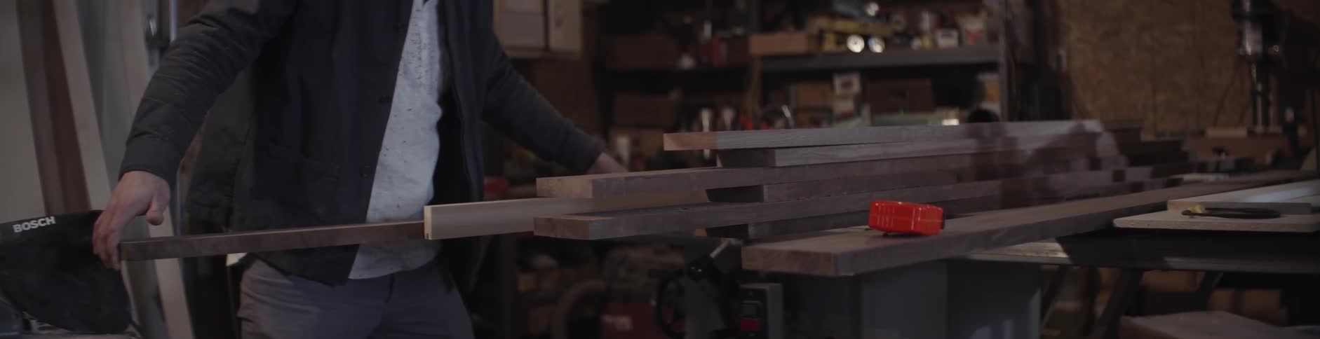 A man stands near a pile of lumber