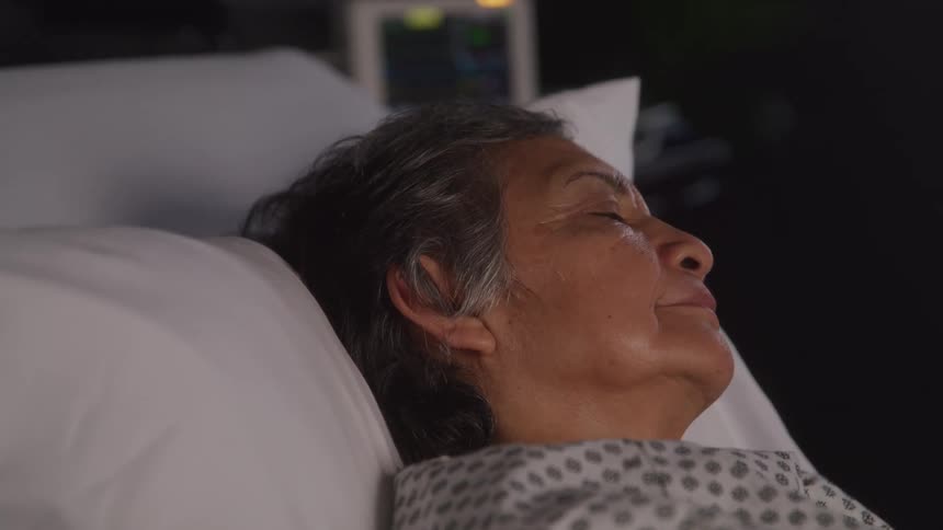 Close up of an elderly female patient nodding while lying down on a hospital bed
