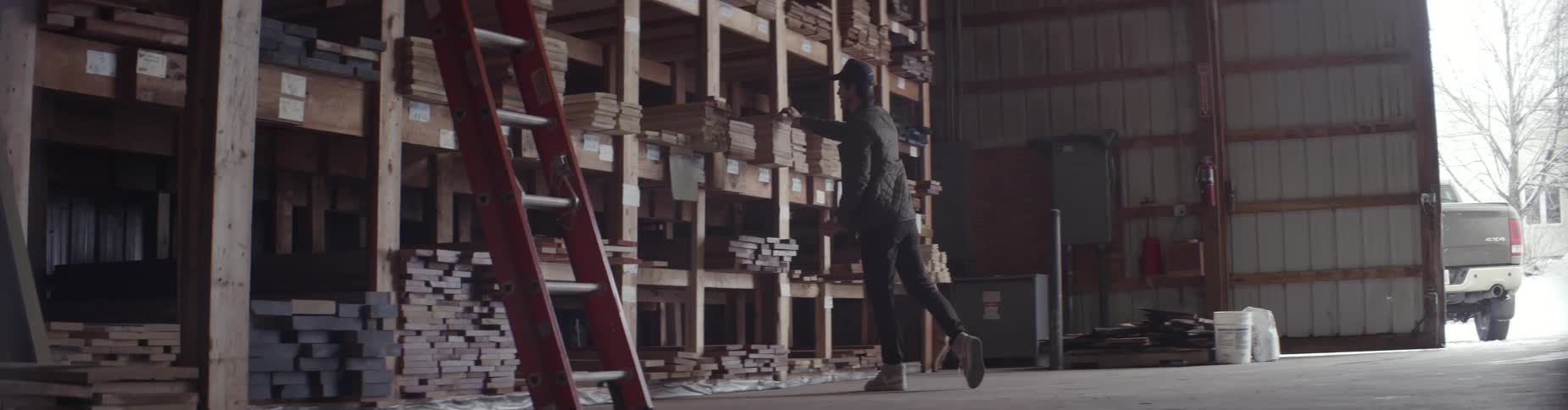 A man pulls a board from a high shelf