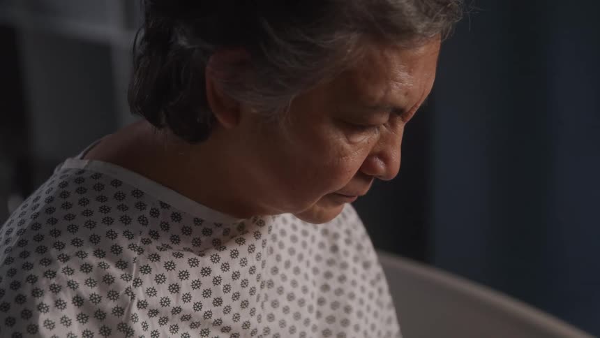 The hospital patient is sitting and looking down