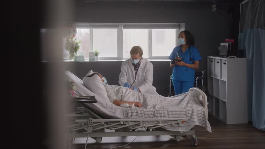 The doctor examines the patient as a nurse writes notes