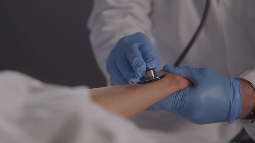 Doctor with gloves and equipment checking a patients pulse