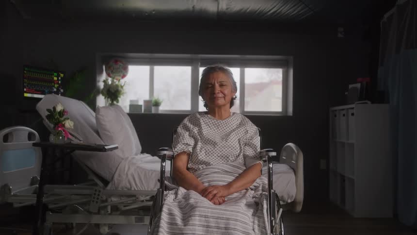Woman in a wheelchair smiles inside a hospital room