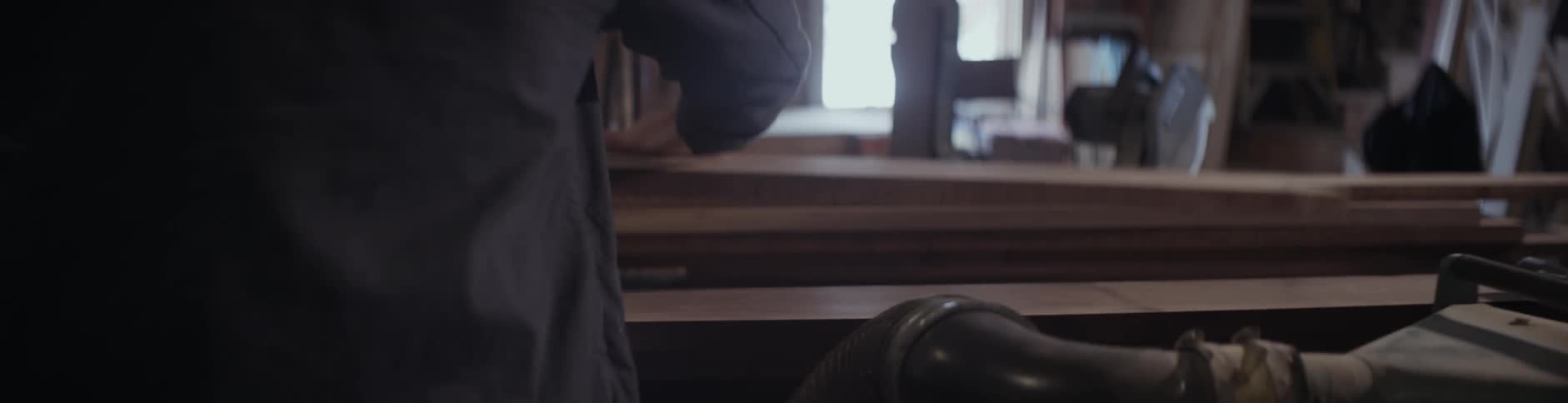 A man pulls wood from a machine