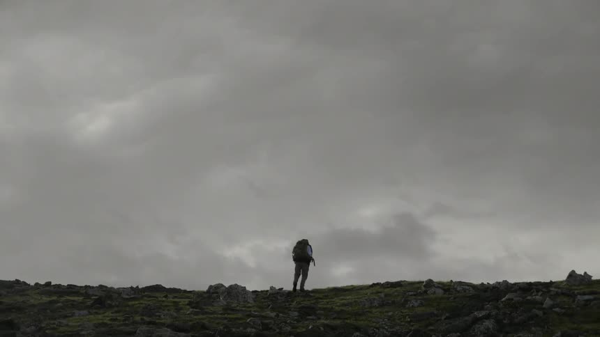 A man hikes to the top of a hill