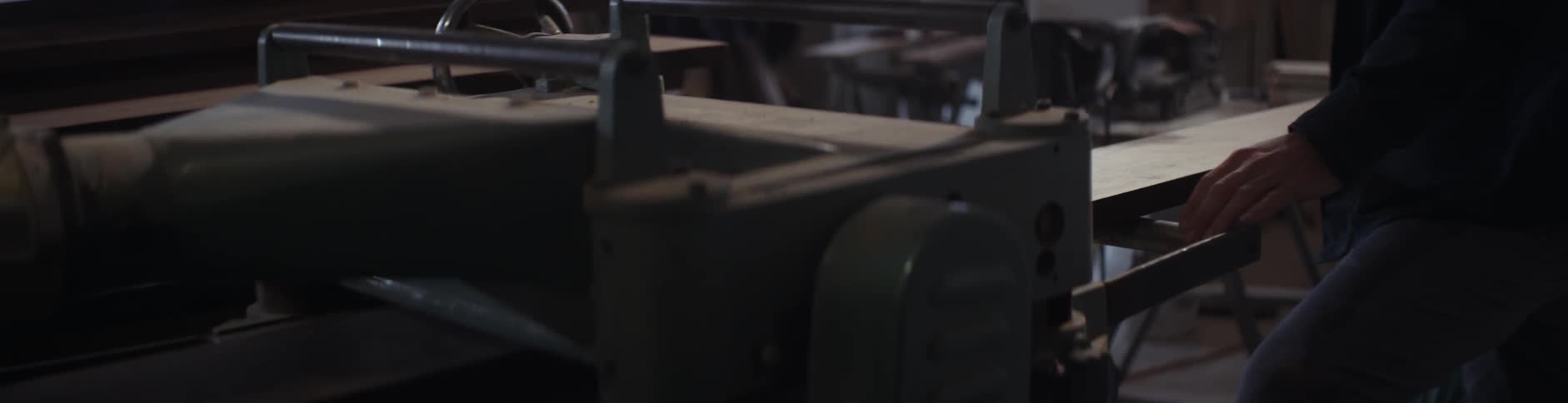 A man feeds a plank into a machine