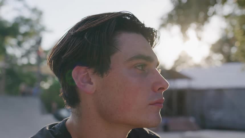 A young man standing outside and gazing in the distance