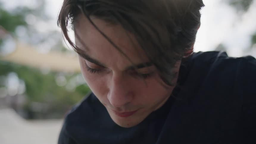 Man looking down with a focused expression outdoors