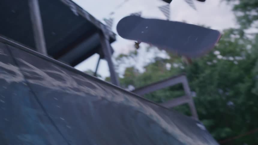 A person rides a skateboard side to side on a vert ramp in a skateboarding park at midday