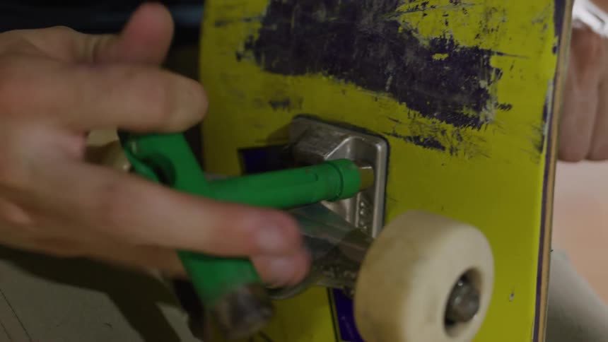 A skateboard is being repaired with a tool