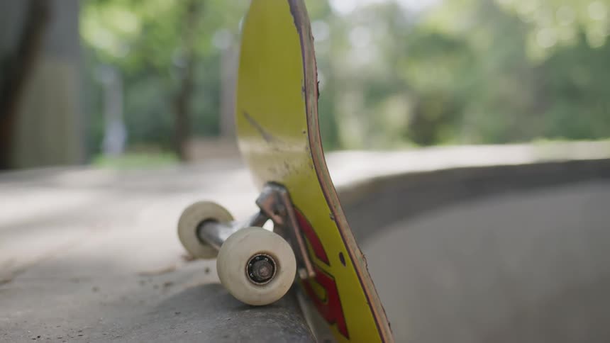 Yellow skateboard hanging off the edge of a an empty swimming pool