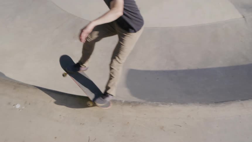 The video shows an empty concrete skate bowl the sun casts shadows on the smooth curved surface of the bowl