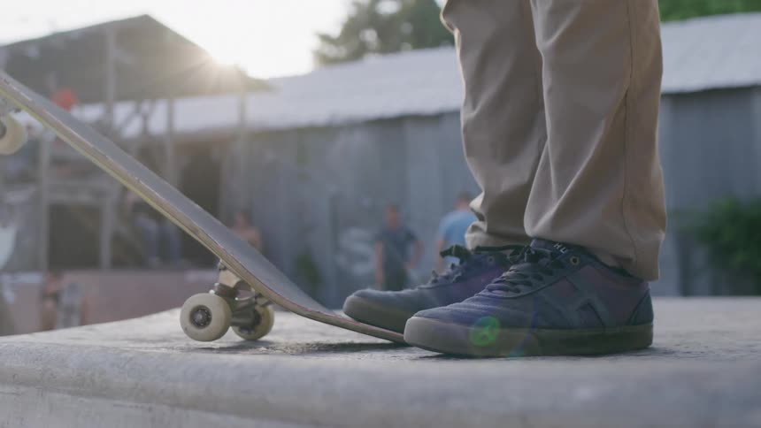 Close up of a person standing on the edge of their skateboard on a platform outdoors during daytime