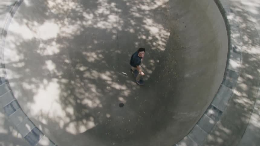 Young man skateboarding inside a bowlshaped empty pool