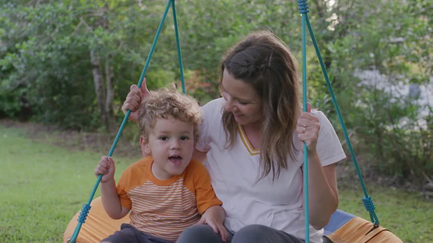 Mother and son sway gently in a swing in the yard on a summer day